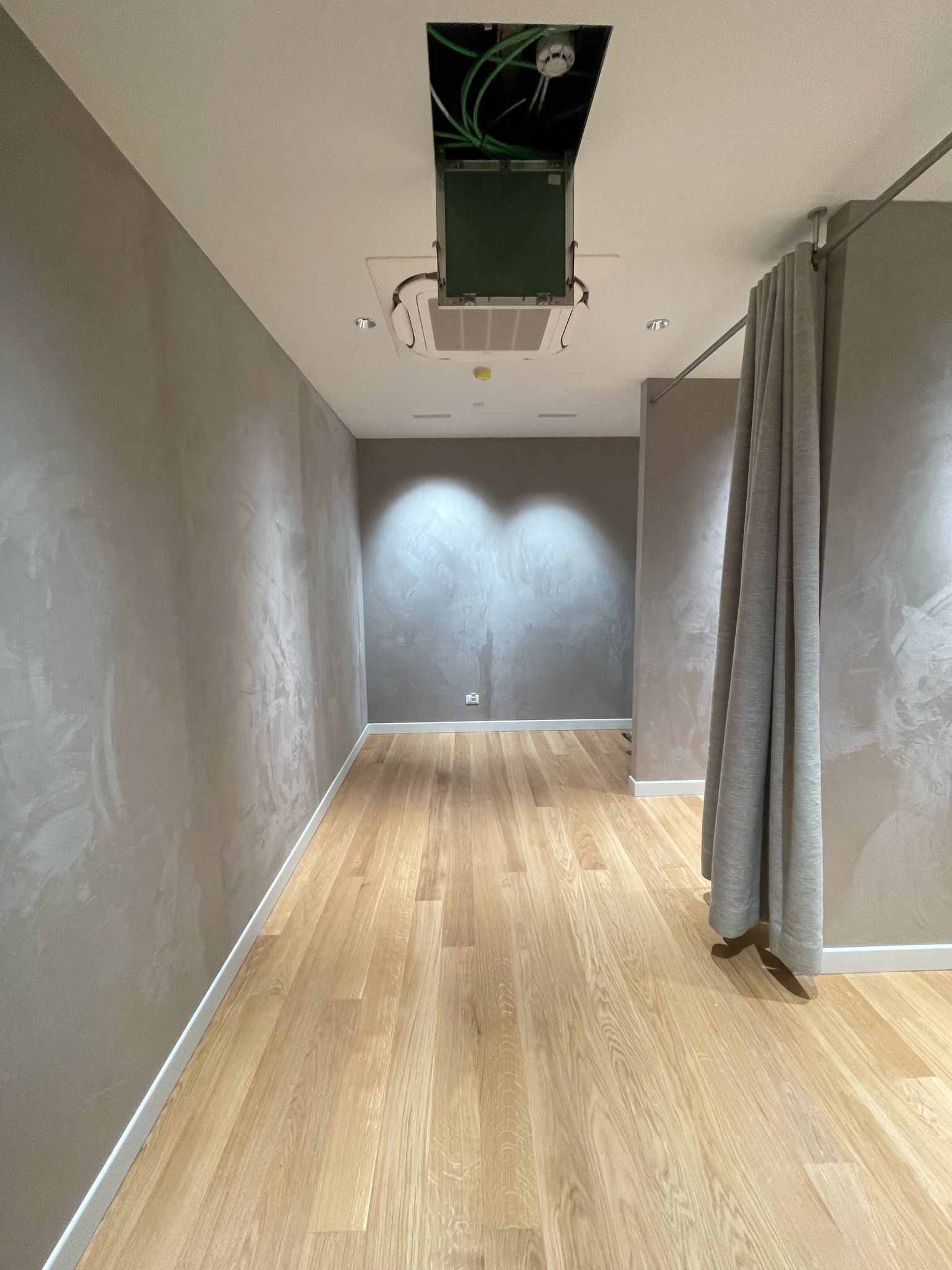 Un lungo corridoio con pavimenti in legno e un ventilatore a soffitto.