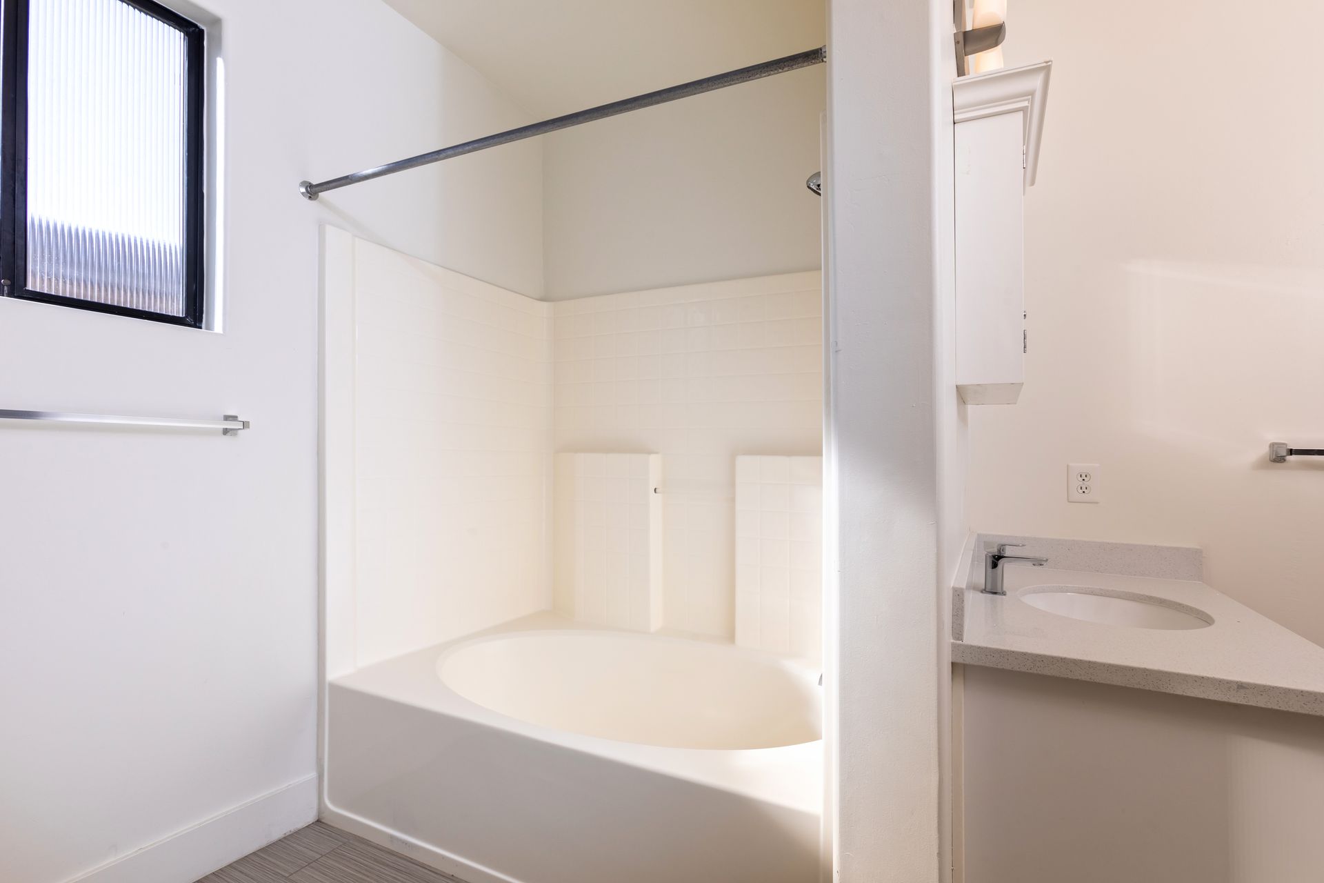 A bathroom with a tub , sink , and window.