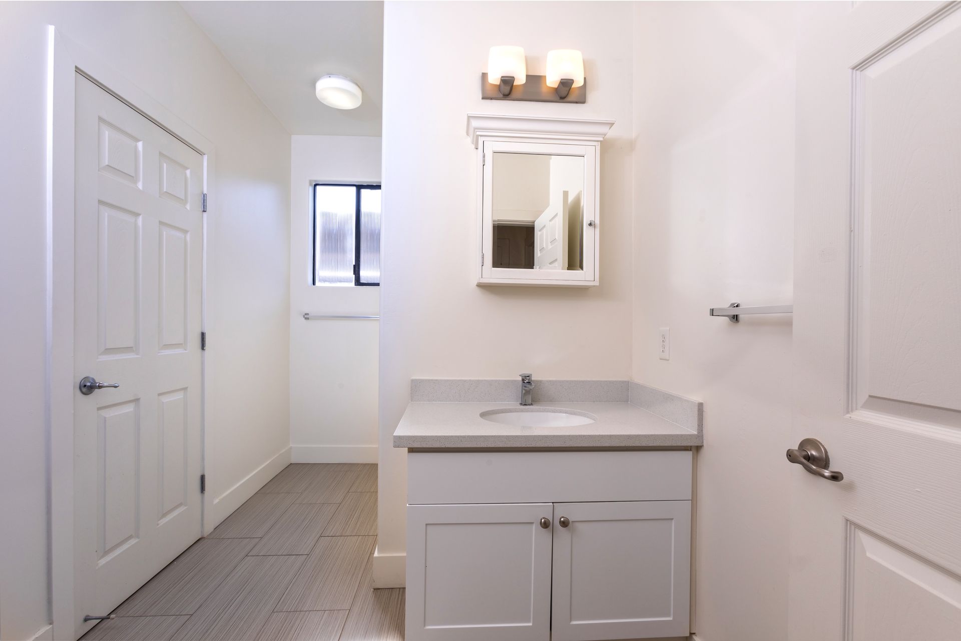 A bathroom with a sink , mirror and door.