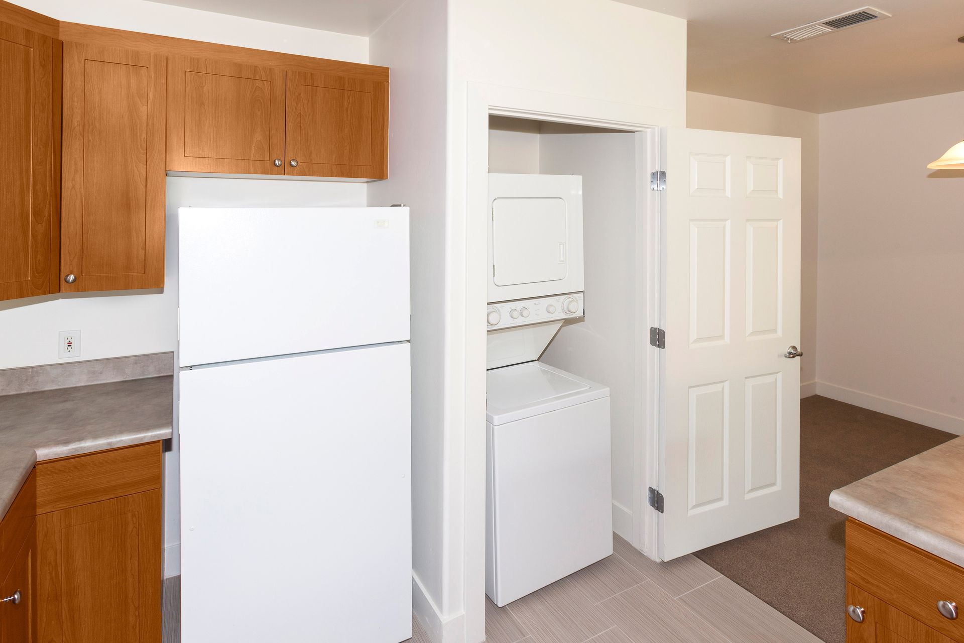 A kitchen with a refrigerator , washer and dryer , and cabinets.