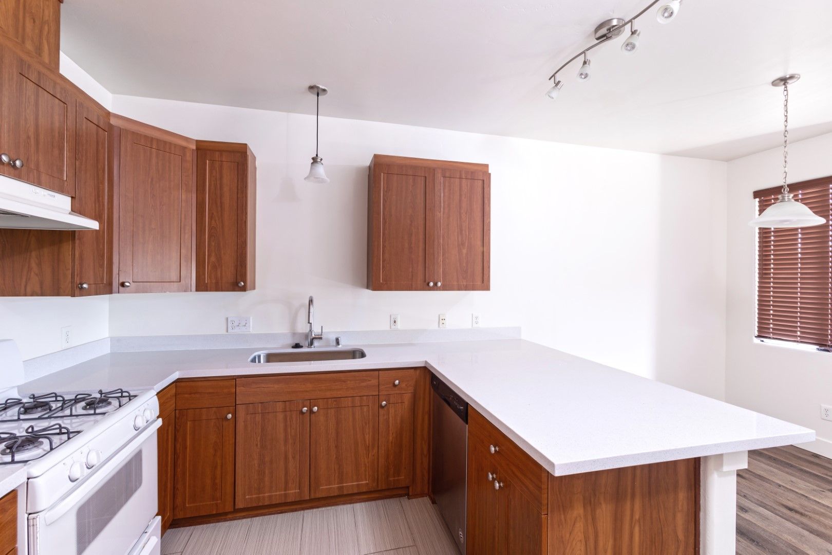 An empty kitchen with wooden cabinets and white counter tops