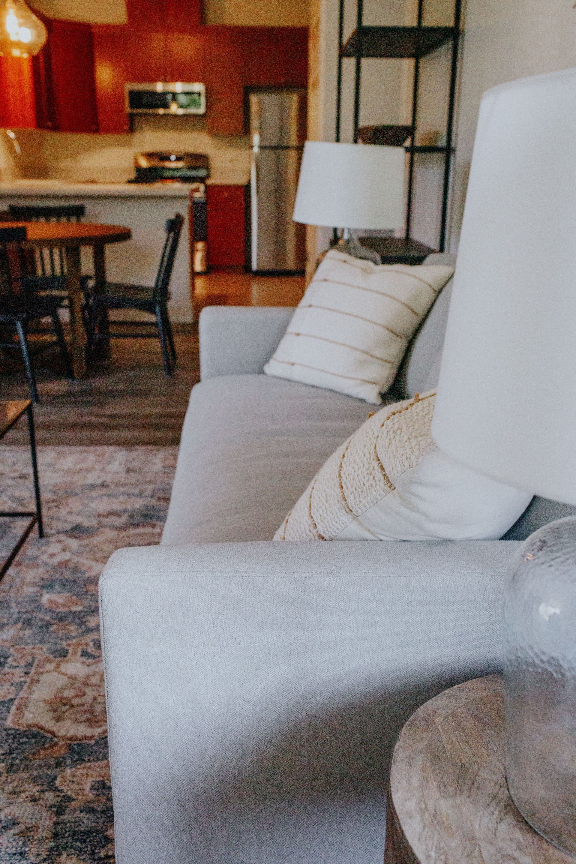 A living room with a couch , chair , table and lamp.