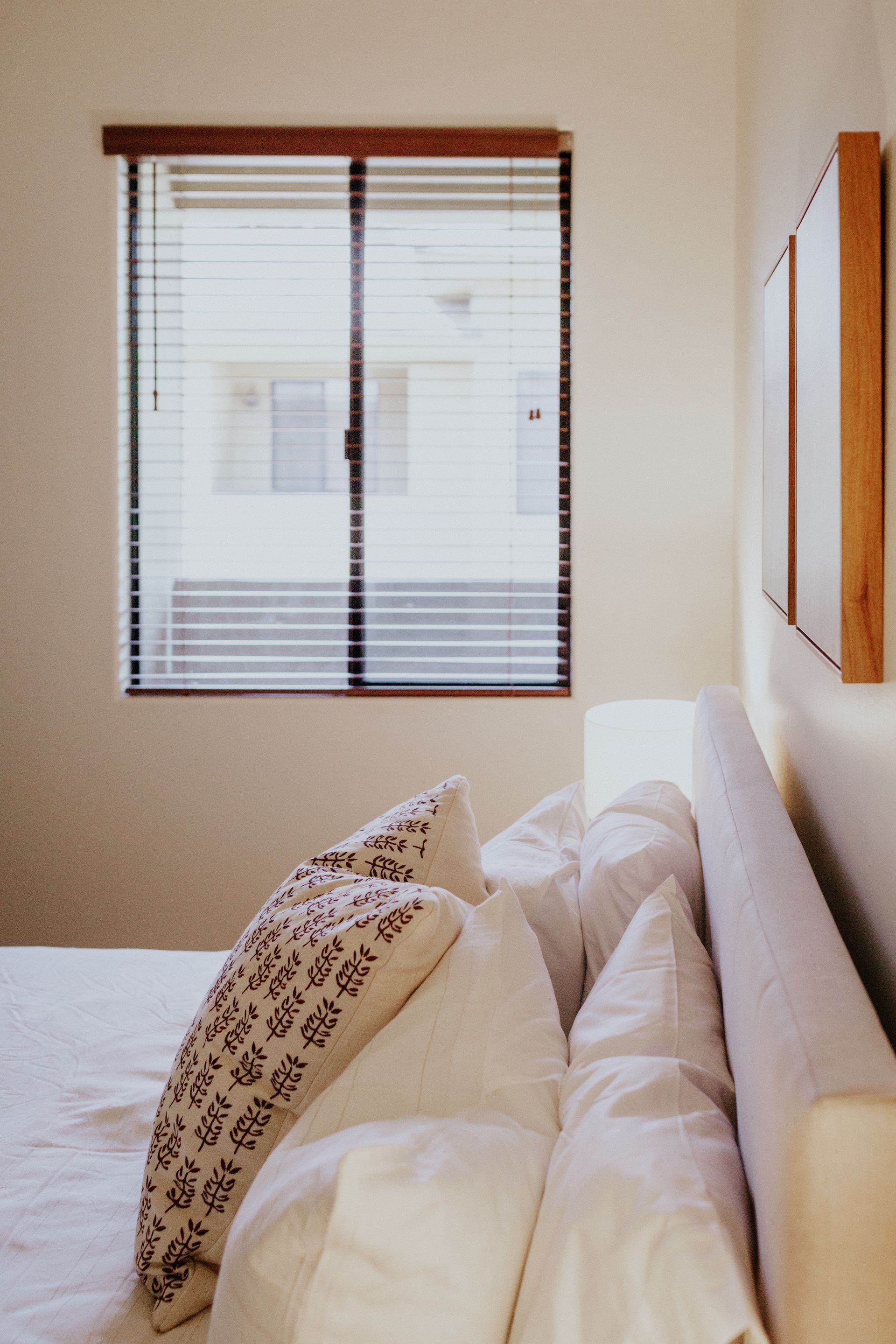 A bedroom with a bed and a window with blinds.