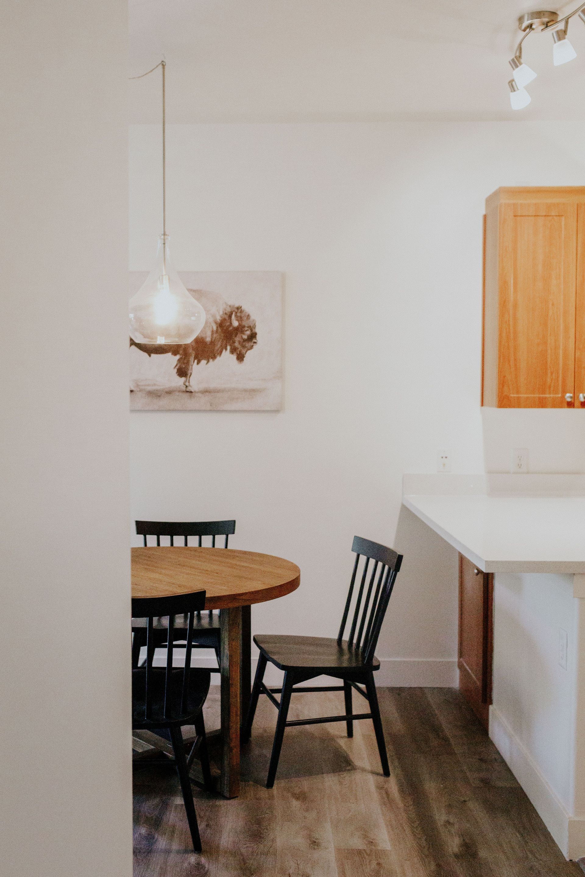 A dining room with a table and chairs and a painting on the wall.