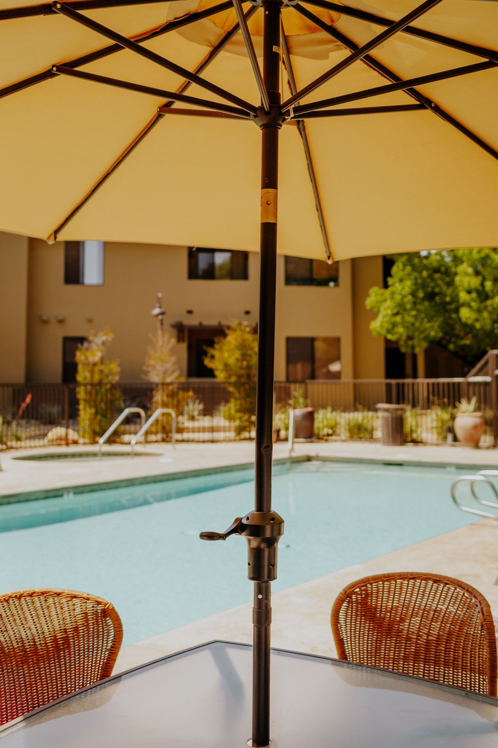 A table with chairs under an umbrella next to a pool