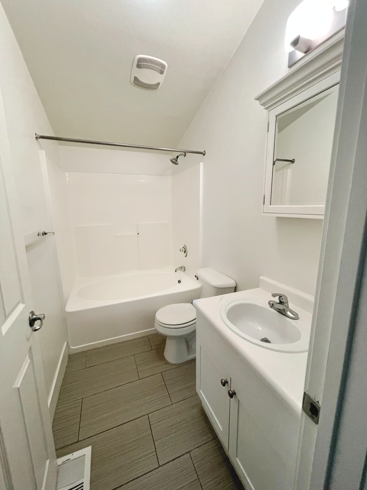 A bathroom with a sink , toilet , bathtub and mirror.