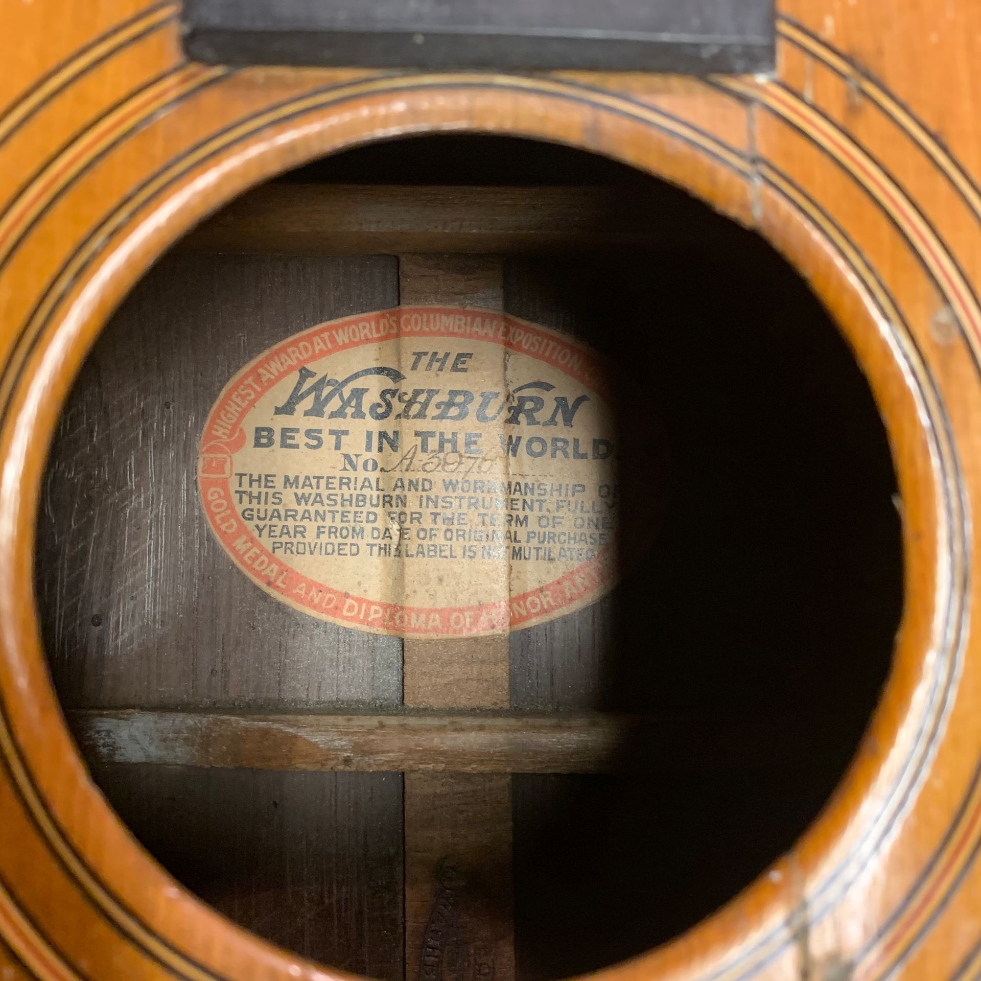 Close-up of a Washburn guitar's soundhole, revealing a circular label with text.