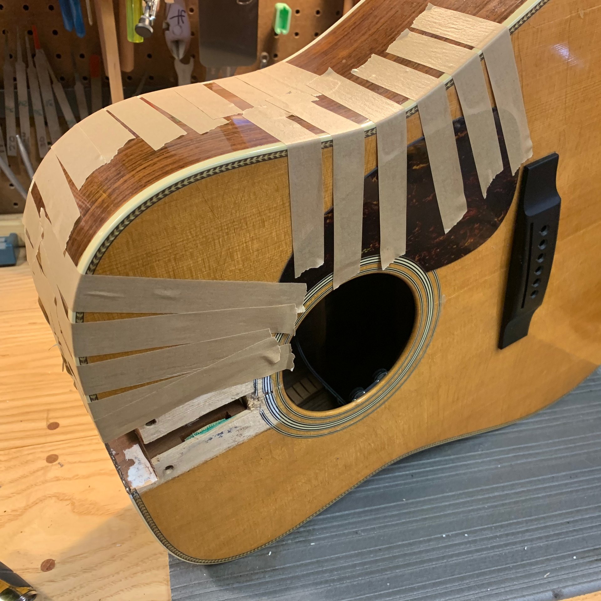 Guitar with masking tape around its soundhole and body. Repair in progress.