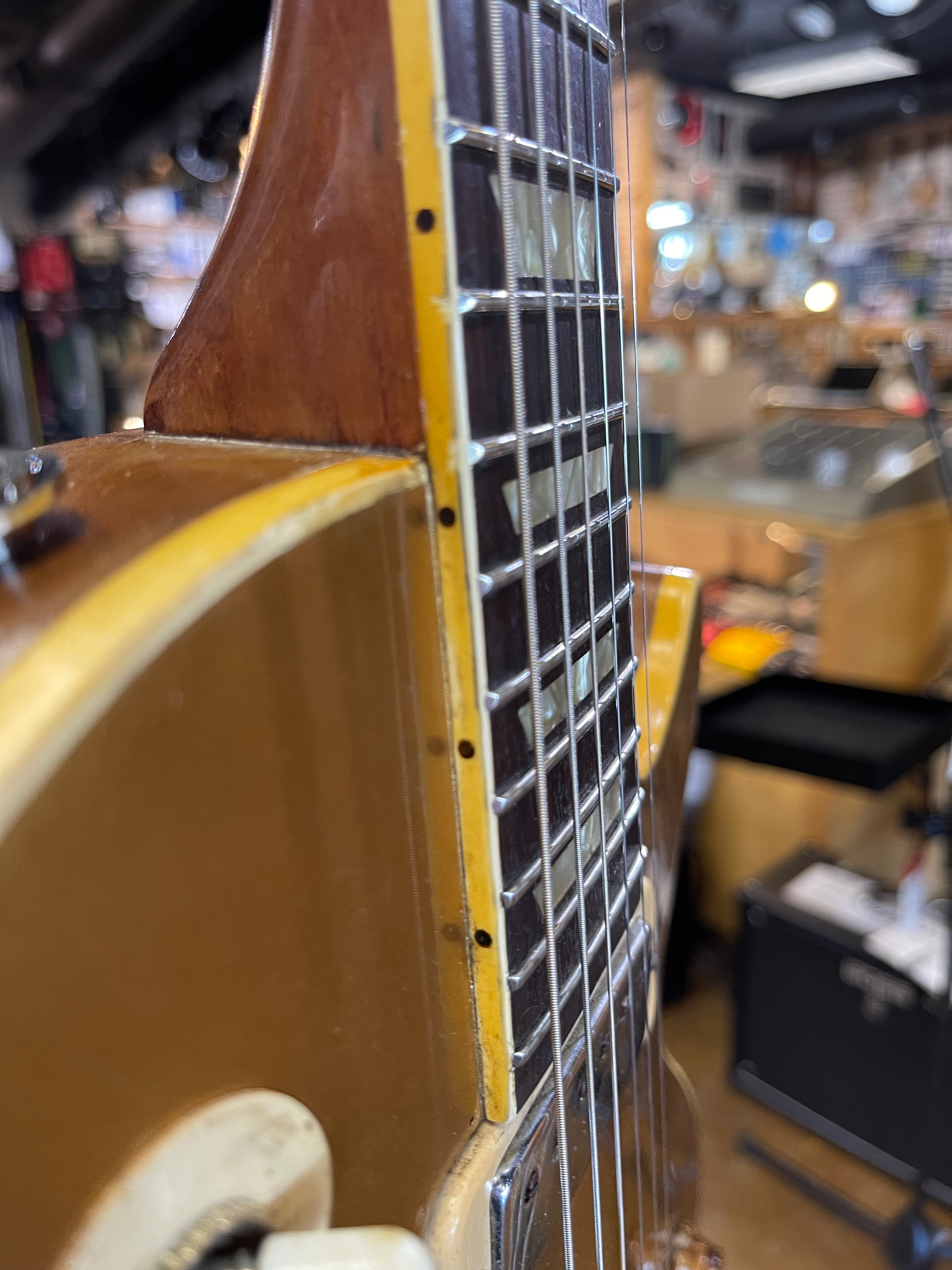 Close-up of a gold electric guitar neck, showing frets, inlays, and binding.