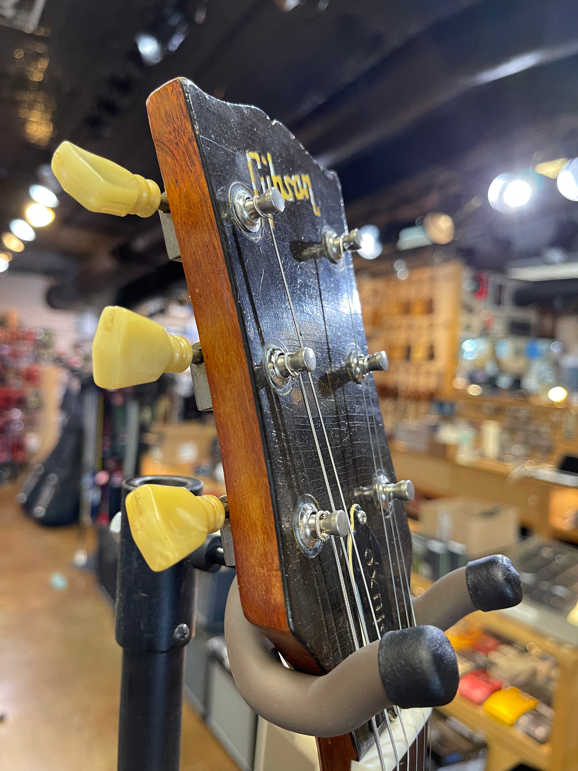 A vintage Gibson guitar headstock with cream tuning pegs, indoors.