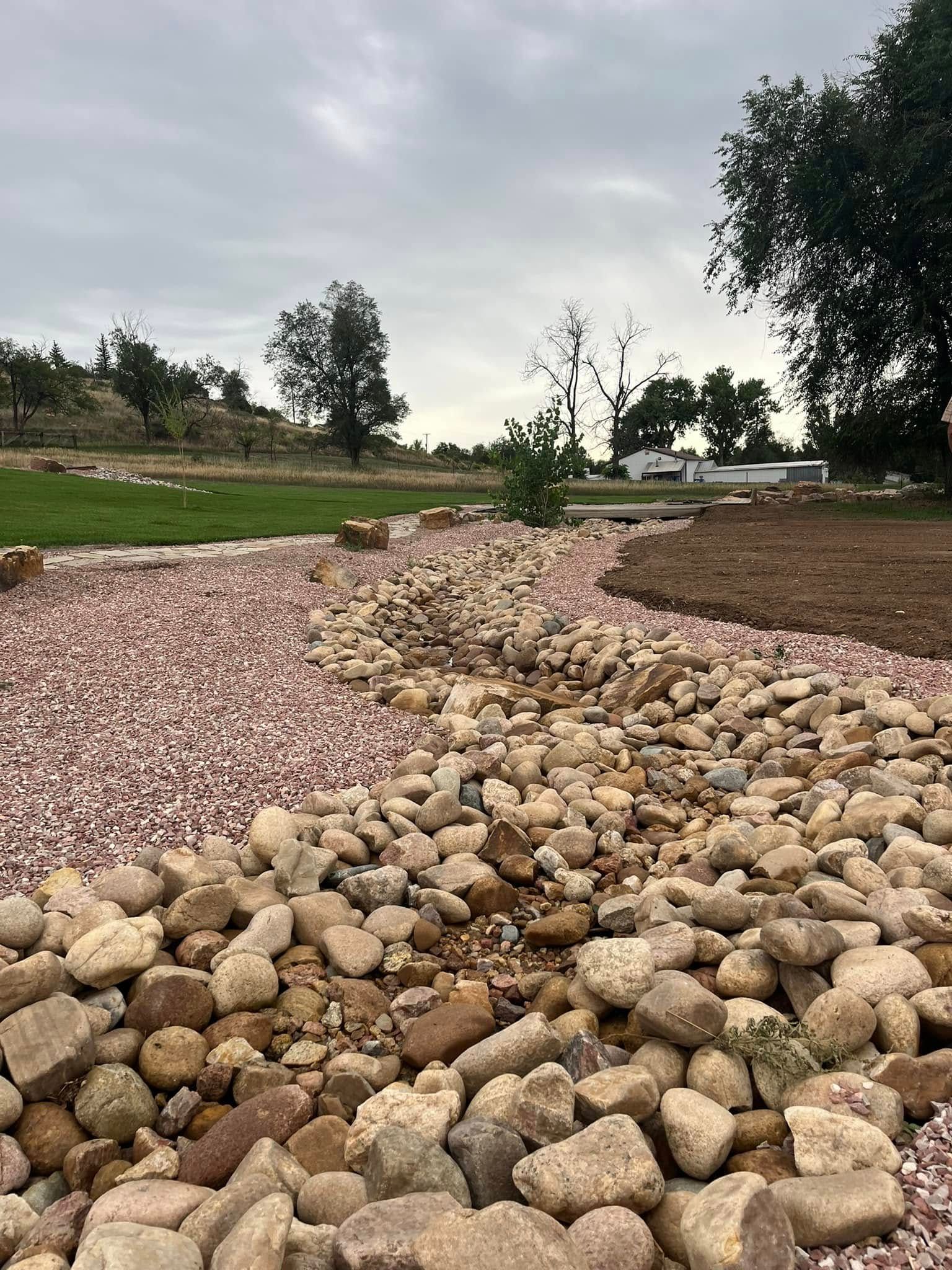 A pile of rocks in a field with trees in the background.