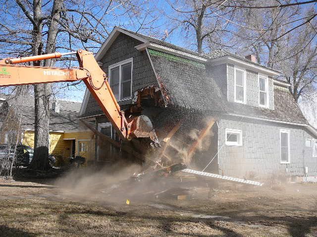 A house is being demolished by an excavator.