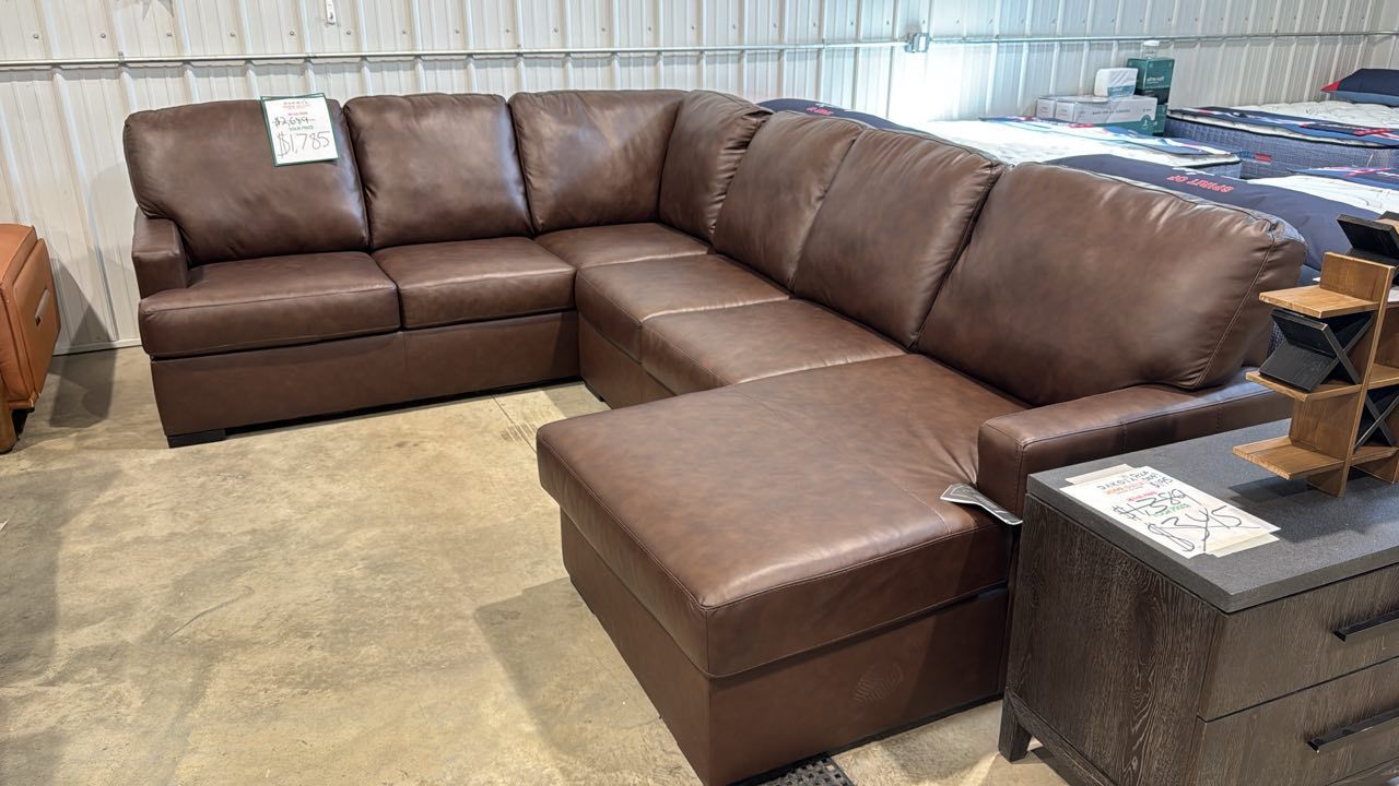 Brown leather sectional sofa with a chaise in a showroom.