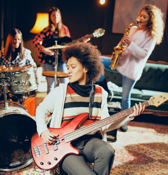 A woman is playing a red guitar in a band