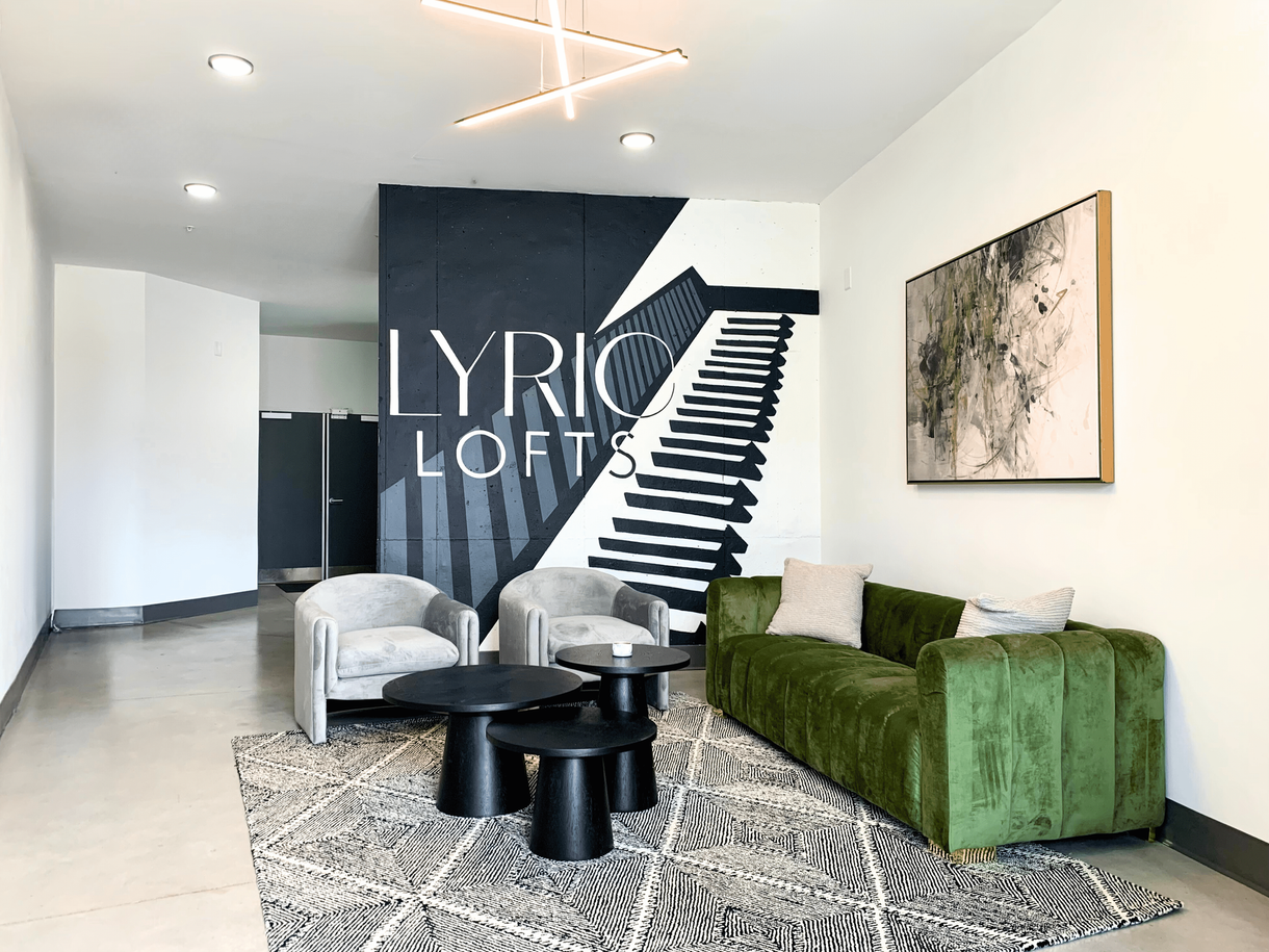 A living room with a green couch , chairs , tables and stairs.