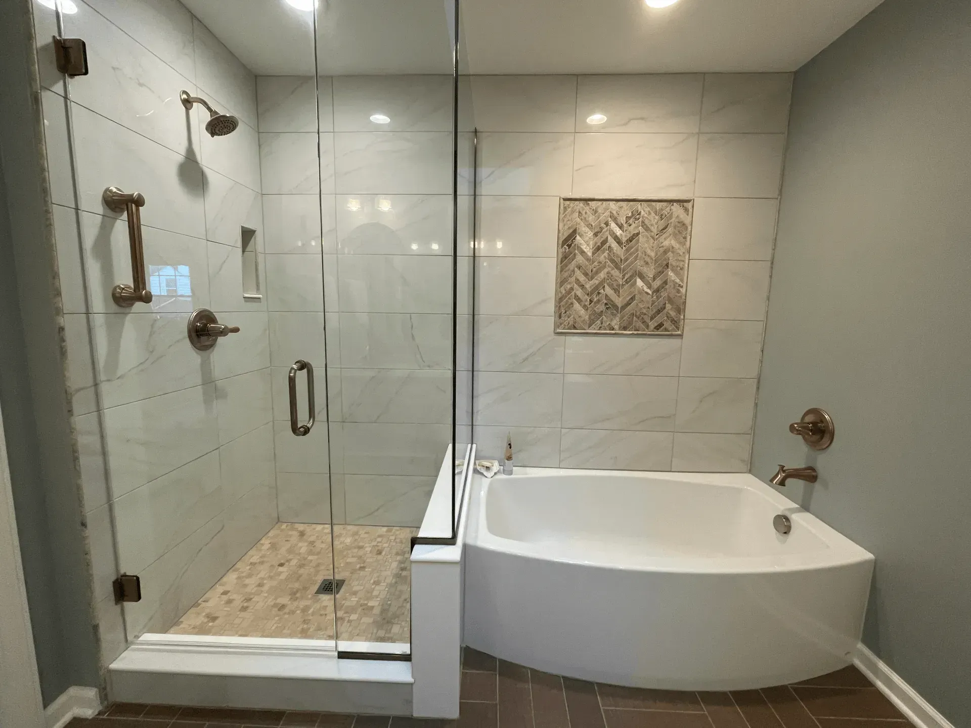 Modern bathroom with a glass-enclosed shower, tub, and neutral tile and wall colors.