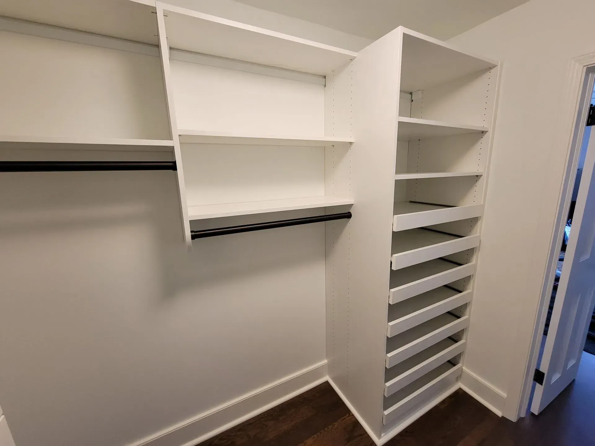 White closet organizer with shelves, hanging rod, and vertical shoe shelves.