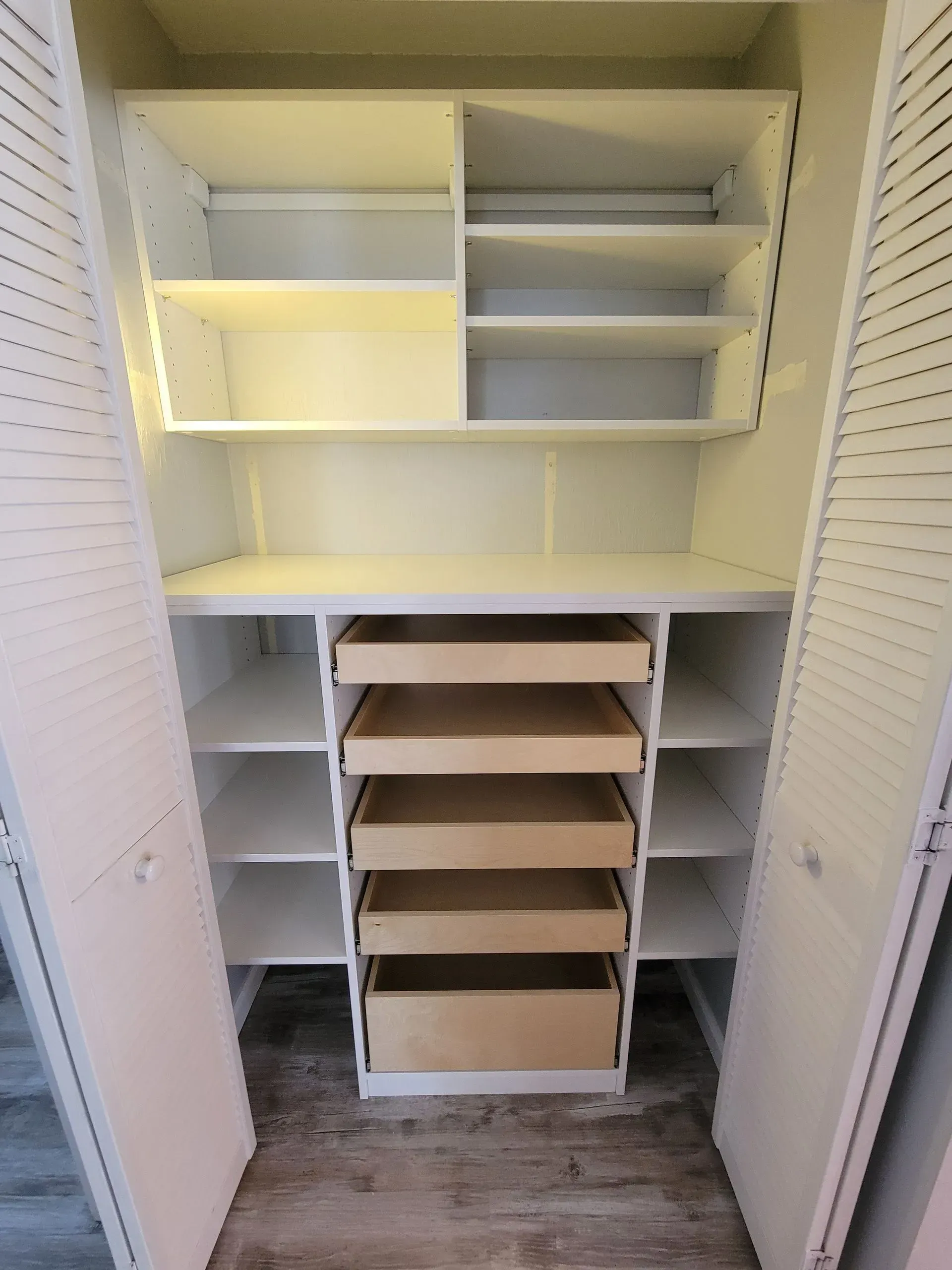 White closet with shelves and drawers, empty and open.