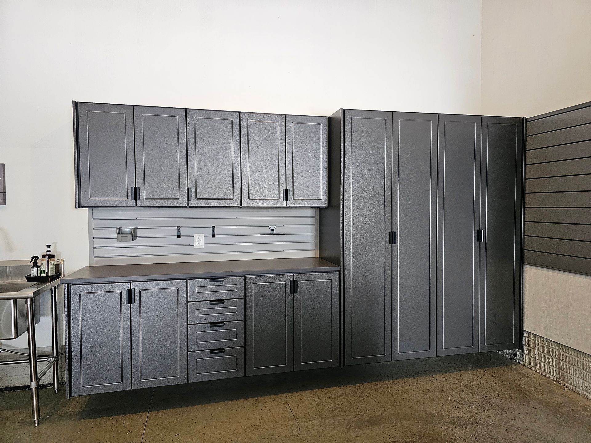 Gray metal garage cabinets and countertop against a white wall; concrete floor.