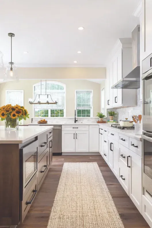 Modern kitchen with white cabinets, brown island, wood floors, and area rug.
