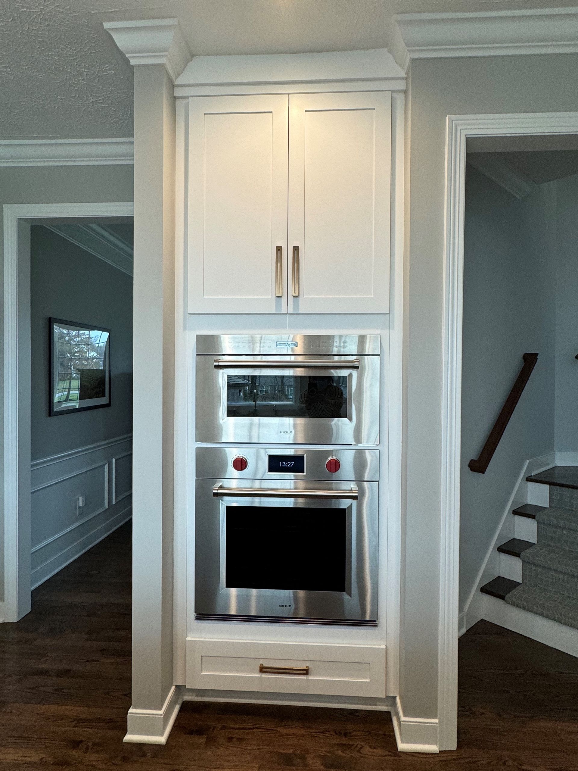 Built-in stainless steel microwave and oven with white cabinetry.