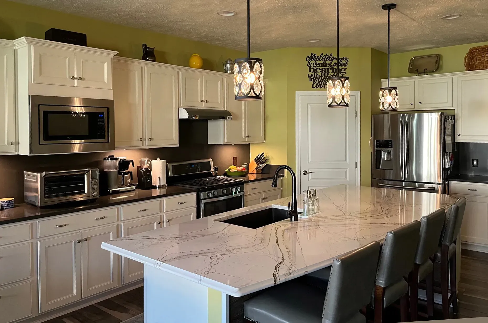 White kitchen with island, dark countertops, and stainless steel appliances.