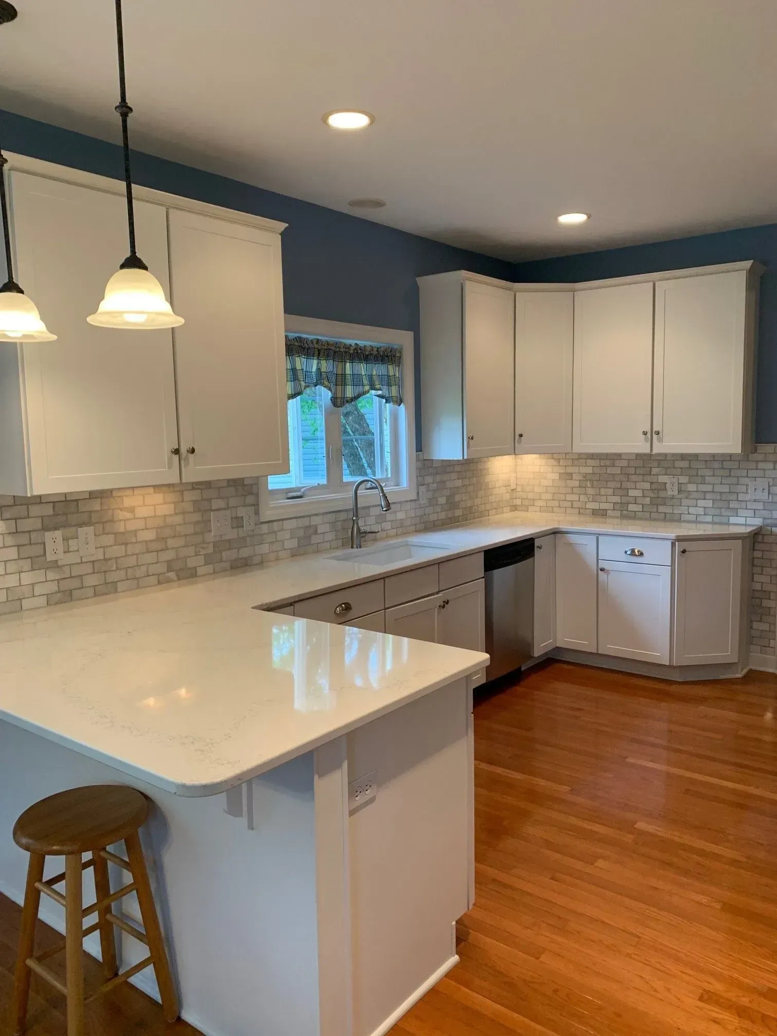 White kitchen with countertops, cabinets, blue wall, wood floor.