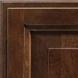 Close-up of a dark brown, wooden cabinet door showing layered molding and wood grain detail.