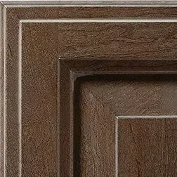 Corner of a brown wood cabinet door with recessed paneling.