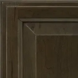 Close-up of a dark brown, textured cabinet door corner with raised panel and molding details.