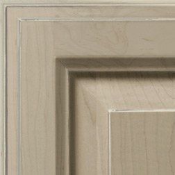 Corner of a light brown wooden cabinet door with layered design and textured grain.