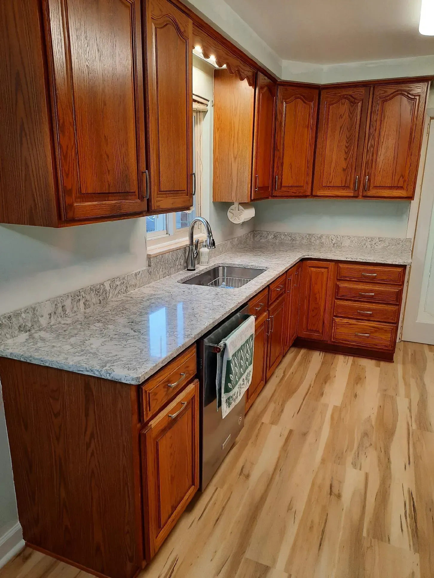 Kitchen with dark wood cabinets, light countertops, and light wood flooring.