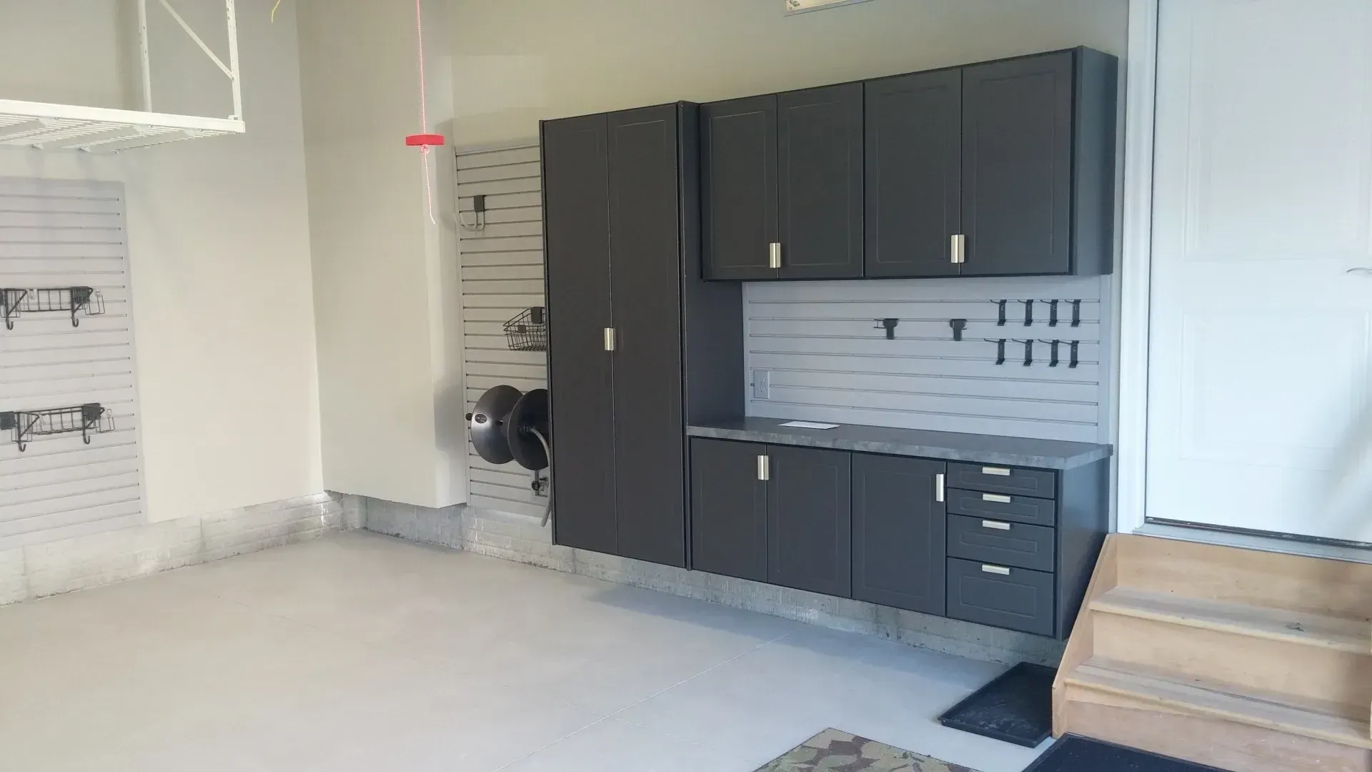 Garage with gray cabinets and workbench, white walls, and a door.