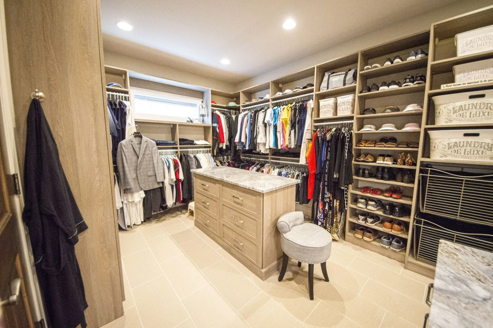 Walk-in closet with neutral wood shelving, clothing racks, and a center island.