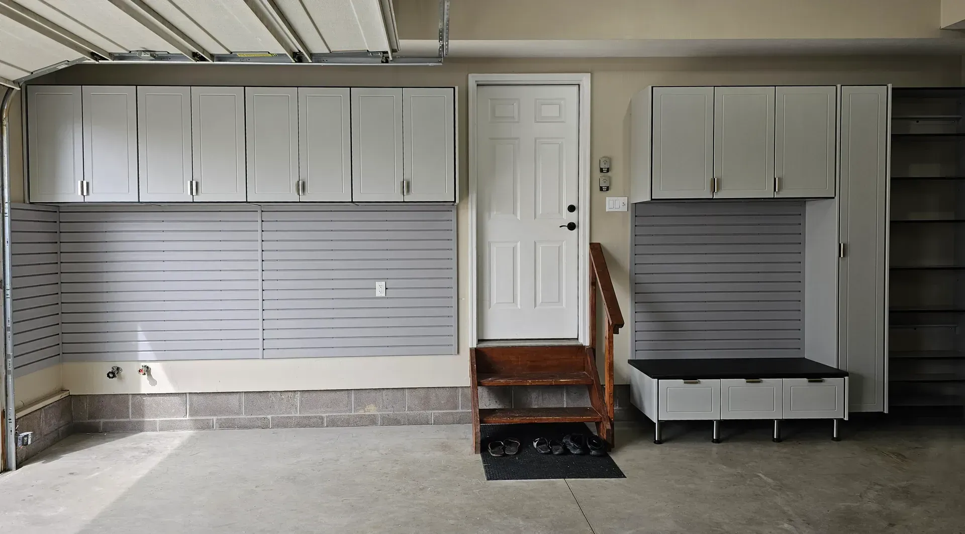 Garage interior with gray cabinets, pegboards, and a door with steps.