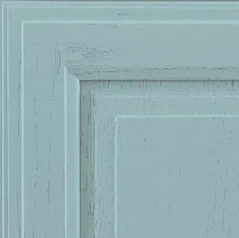 Close-up of a light blue, distressed cabinet door corner.