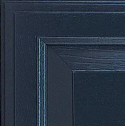 Close-up of a navy blue cabinet door corner with visible wood grain and layered trim.
