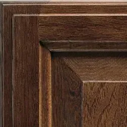 Close-up of dark brown, wooden cabinet door with raised paneling and a textured grain.