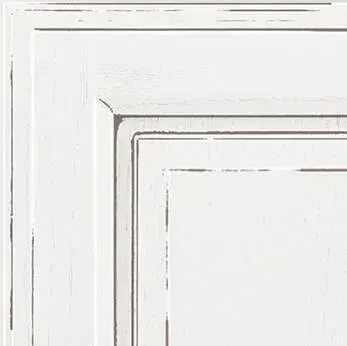 Corner of a white, distressed cabinet door with recessed panels.