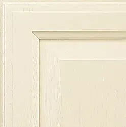 Cream-colored cabinet door corner with raised panel, showing details of molding and painted wood texture.