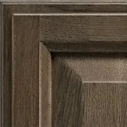 Close-up of a wooden cabinet door with a dark brown stain and raised panel.