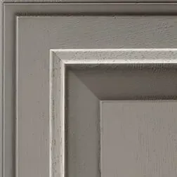 Corner of a gray cabinet door with raised panel and detailed trim.
