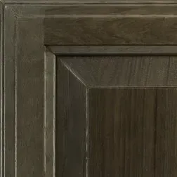 Close-up of a dark stained wood cabinet door corner. Vertical wood grain is visible.