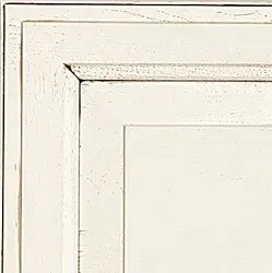 Close-up of a white, distressed cabinet door with raised panel details.