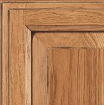 Close-up of a wooden cabinet door corner. Light brown wood grain with framed panels.