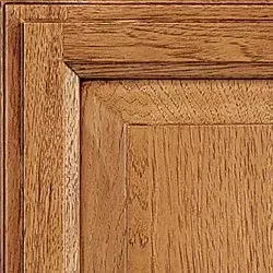 Close-up of a wooden cabinet door with visible grain, medium brown, angled framing around the panel.