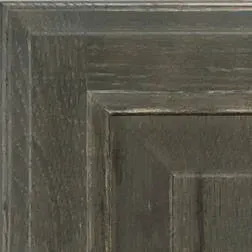 Close-up of a weathered, grey wooden cabinet door corner.