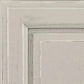 Close-up of a distressed, light gray cabinet door with a raised panel design.