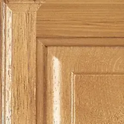 Close-up of wooden cabinet door corner with raised panel and decorative trim.