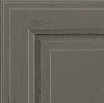 Close-up of a weathered, gray-painted cabinet door with raised panels and detailed trim.